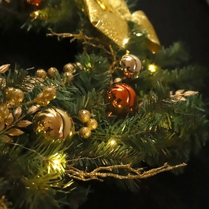 Golden Christmas ball PVC garland with LED lights and festive bows on dark background