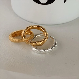 Detail of minimalist silver and gold knot rings set on a white ceramic background