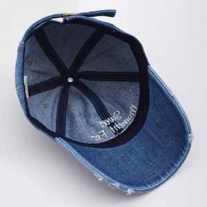 Detail der blauen Denim-Baseballkappe mit Metallschnalle und abgenutzter Krempe