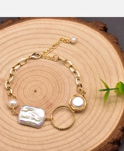 Detail of baroque pearl bracelet with gold lobster clasp on a wooden background