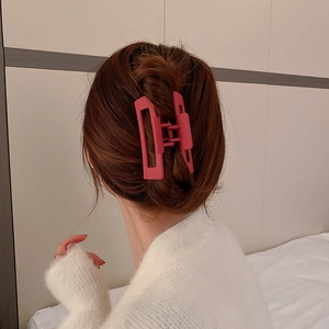 Détail d'une pince à cheveux géométrique rouge rose mat portée par une femme