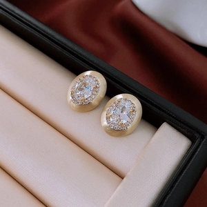 Détail de boucles d'oreilles ovales en or mat avec cristaux halo en vue macro