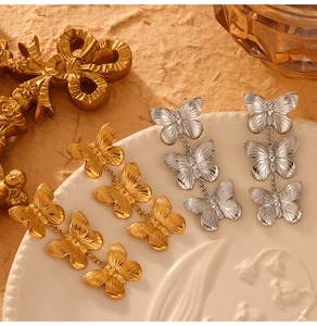 Détail de boucles d'oreilles pendantes papillons en finitions or et argent brossé