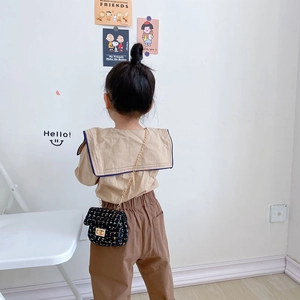 Kids quilted black crossbody bag with gold chain and tweed texture on beige outfit