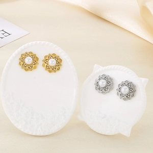 Flower shaped titanium steel earrings with pearls in gold and silver finish on silk background