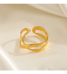 Detail of a minimalist gold crossover ring with handcrafted hammered texture finish