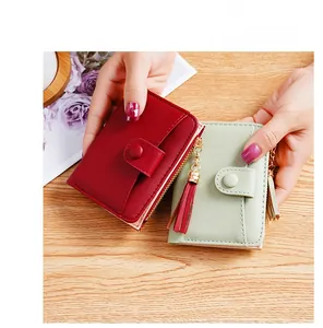 Detail of compact mini wallets with smooth texture, snap closure and tassel pendants