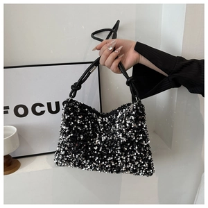 Detail of a chic handbag featuring shimmering black sequins and a knotted leather handle