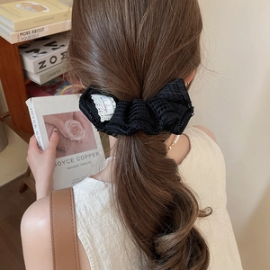 Détail d'un chouchou noeud en dentelle noire porté sur de longs cheveux avec lumière douce