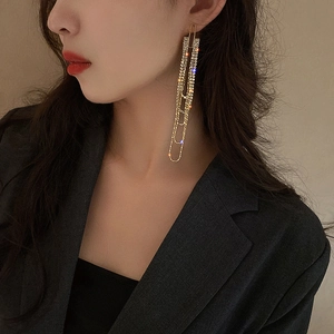 Golden long chain tassel earrings with sparkling rhinestones worn by a model