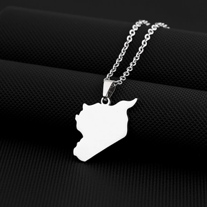 Macro shot of silver map pendant necklace on black textured background showing metallic detail
