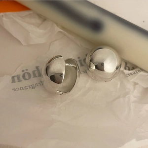 Macro shot of S925 sterling silver ball earrings showing smooth mirror finish and stamp