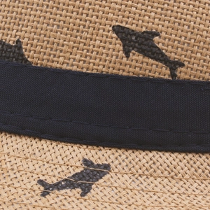 Detailed close-up of woven yellow straw sun hat featuring black fish silhouette patterns