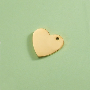 Vue détaillée d'un pendentif cœur doré minimaliste en acier inoxydable sur un fond texturé