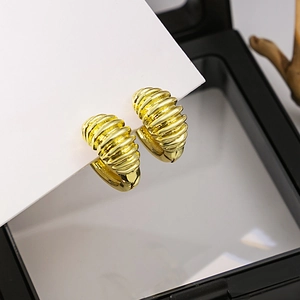 Boucles d'oreilles créoles dorées avec texture spirale sur carte blanche