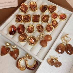 Detail of amber resin heart and geometric earrings with gold trim in a jewelry tray