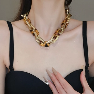 Dettaglio di una collana a catena dorata con maglie in resina tartarugata indossata