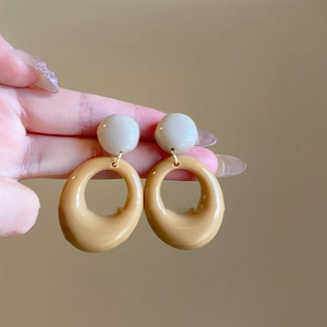 Close-up of caramel and beige geometric resin hoop earrings with a glossy finish