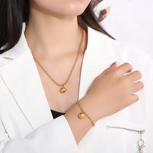 Close-up of a gold stainless steel beaded necklace and bracelet set worn by a woman