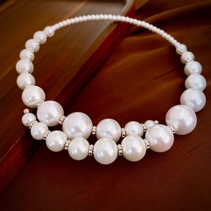 Macro detail of gradient pearl choker with silver spacers on vintage fabric