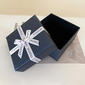 Detail of navy blue jewelry gift box with white satin ribbon bow and black velvet foam insert