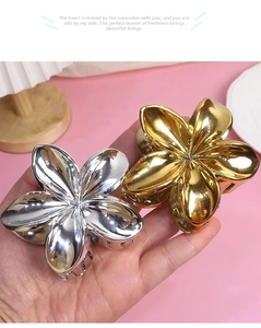 Detailed close-up of metallic flower hair claw clips in elegant gold and silver finishes