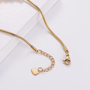 Minimalist gold heart snake chain bracelet with adjustable lobster clasp on white stone