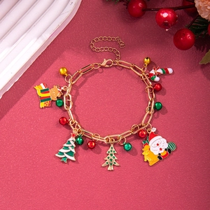 Detailed shot of Christmas charm bracelet with enamel Santa, tree and bell on red background