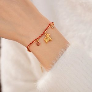 Detail of 18K gold plated red rope bracelet featuring a zodiac dog and coin pendant