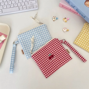 Close-up of colorful checkered canvas storage pouches with embroidered cherry details