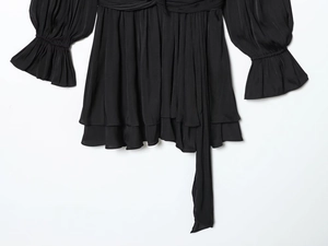 Détail de robe en satin noir avec tissu plissé et poignets à volants multicouches