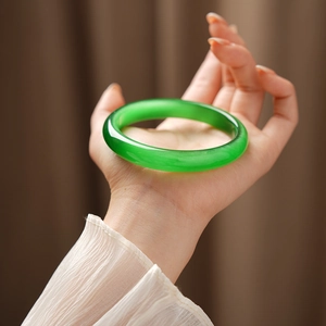 Close-up of green cat-eye stone bangle worn on wrist showing translucent texture