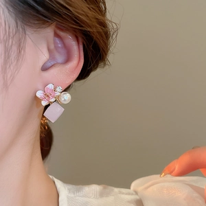 Close-up of pink floral pearl earring with rhinestone and geometric charm on model