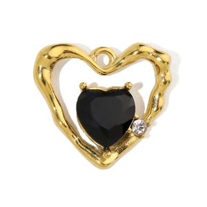 Macro detail of a heart-shaped pendant featuring a golden frame and black stone inlay