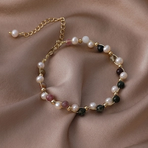Detailed close-up of handmade baroque pearl bracelet with colorful natural stones and silk