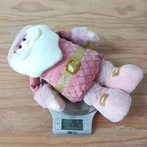 Pink plush Santa Claus figurine weight measurement of 282.5g on a digital kitchen scale