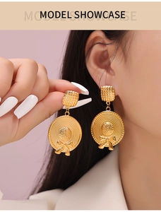 Close-up of golden straw hat dangle earring with bow detail on a fashion model