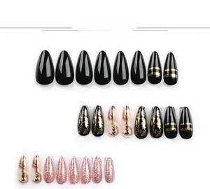 Detailed view of pointed almond press-on nails with black gold foil and diamond accents