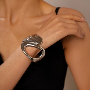 Polished silver geometric bangle featuring an artistic asymmetrical open design on a wrist