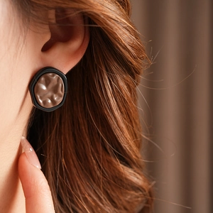 Close-up of a model wearing minimalist geometric brown earrings with black borders