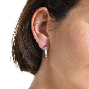Detail of silver stainless steel hoop earrings with flat rectangular profile on model