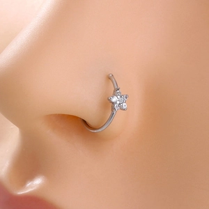 Macro shot of a silver star nose ring with white zircon on a model's piercing