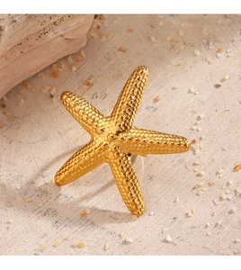Detailed view of golden starfish ring with grainy texture on a sandy beach setting