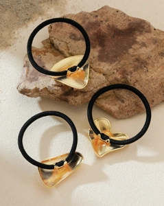 Detailed view of three black elastic hair ties with textured gold metal heart charms