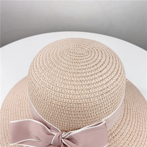 Detailaufnahme der Strohhut-Webstruktur mit elegantem rosa Band und großer Schleife