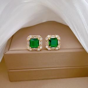 Macro shot of emerald green square earrings with gold frame and white cubic zirconia details