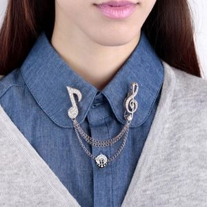Detail of silver music note collar pins with zircon stones and layered metal chains