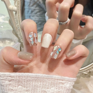 Detailed view of white cat-eye nails with rose gold glitter and holographic sequins