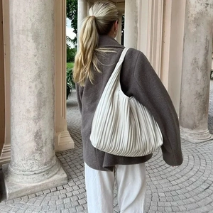 Elegant white pleated shoulder bag shown in an outdoor European street style setting