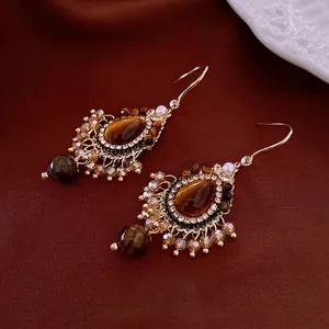 Boucles d'oreilles vintage en œil de tigre avec zircone et perles sur velours rouge
